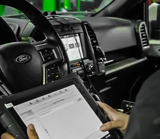 Technician running a diagnostic tablet scan inside a Ford