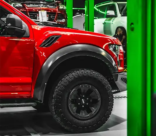 Red Ford F-150 Raptor showing factory-matched paint on the front wing and wheel arch